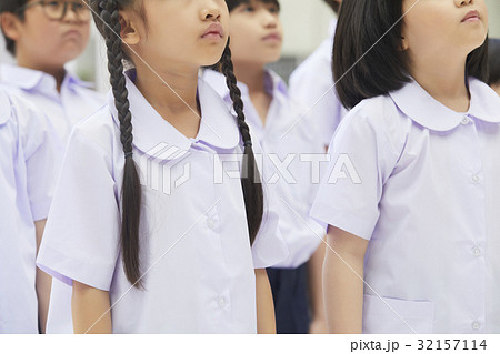 a group of students in uniform is standing together and looking up. 32157114