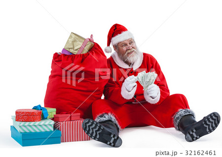 Santa claus sitting next to gift counting a currency note Santa claus sitting next to gift counting a currency note 32162461