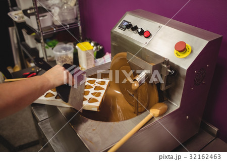 Worker filling mould with melted chocolate Worker filling mould with melted chocolate 32162463