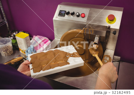 Worker filling mould with melted chocolate Worker filling mould with melted chocolate 32162495
