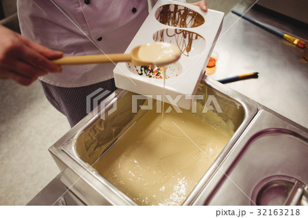 Mid section of worker filling chocolate mould Mid section of worker filling chocolate mould 32163218