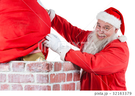Santa claus placing gift box into a chimney 32163379
