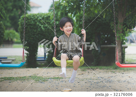 Asian child in kimono playing on swing i 32176006