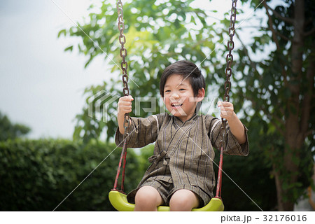 Asian child in kimono playing on swing i 32176016