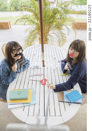 フォトプロップスを持って自撮り棒で撮影をする女子大生 撮影協力 日本経済大学の写真素材