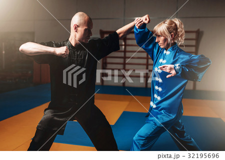 Male and female wushu fighters exercises indoor Male and female wushu fighters exercises indoor 32195696