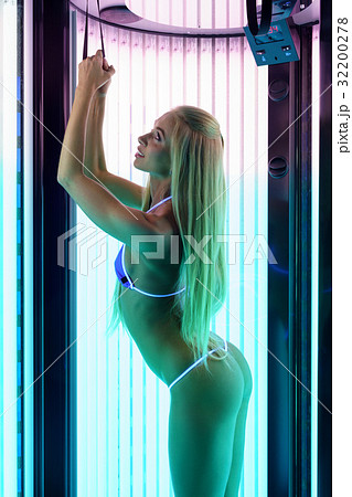 Tanning procedure. Slender woman tans in solarium Tanning procedure. Slender woman tans in solarium 32200278