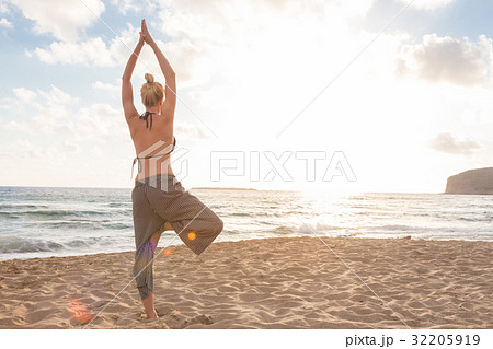 Woman practicing yoga on sea beach at sunset. 32205919