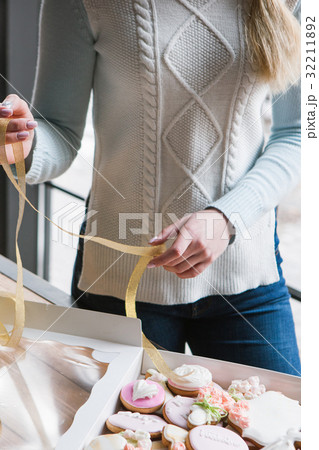 Girl decorating gingerbread box with ribbon 32211892