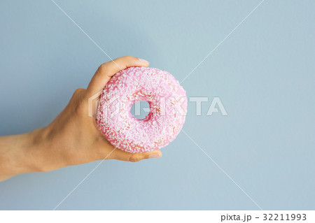 Woman holding pink delicious donut on blue 32211993