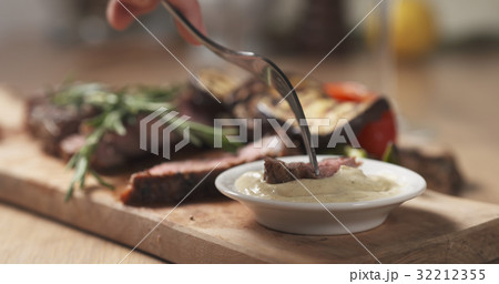 cutting piece from rib eye steak and dip sauce 32212355