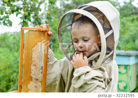 The boy beekeeper saves fresh honey from a honey The boy beekeeper saves fresh honey from a honey 32212595