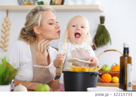 Mother kiss her child daughter while cooking pasta 32215735