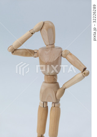 Confused wooden figurine standing with hand on head 32226289