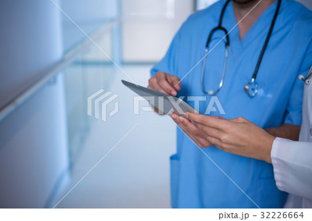 Mid section of doctor and nurse using digital tablet in corridor 32226664