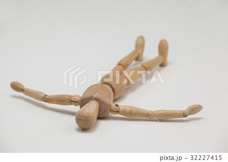 Wooden figurine lying on floor with arms spread 32227415