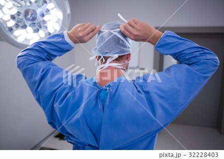Surgeon tying surgical mask in operation room 32228403