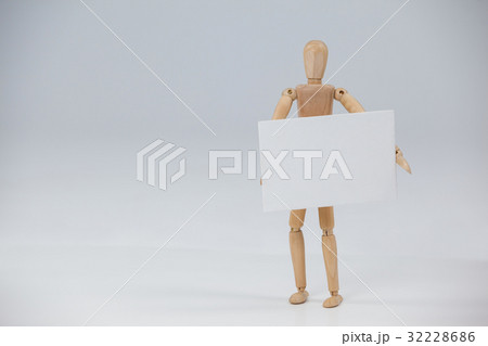Wooden figurine standing and holding a white placard 32228686