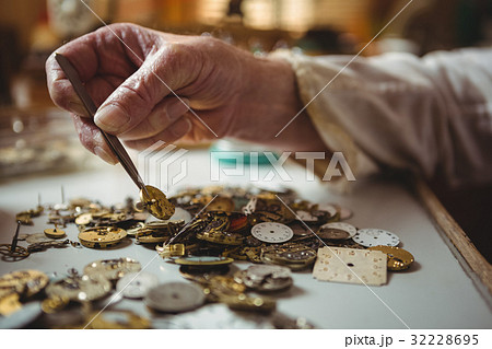 Horologist selecting a clock dial with tweezers 32228695