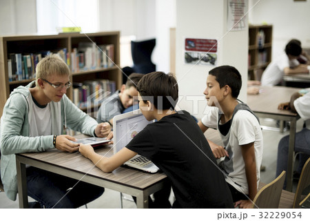 Group of diverse high school students using laptop in library 32229054