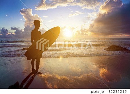 surfer man standing on beach  holding  surfboard 32235216