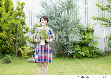 庭で植木鉢を持つ若い女性 32236442