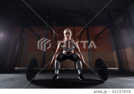 Muscular young fitness woman lifting a weight in 32237058
