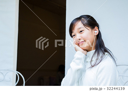 スマホを使っている女の子 イヤホンをしている女の子 女性 中学生 ハウススタジオ 家 の写真素材