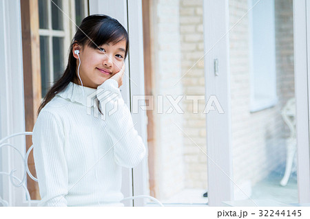 スマホを使っている女の子 イヤホンをしている女の子 女性 中学生 ハウススタジオ 家 の写真素材