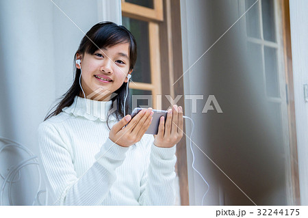 スマホを使っている女の子　イヤホンをしている女の子　女性　中学生　ハウススタジオ　家　 32244175