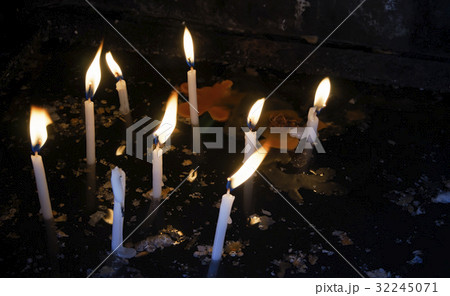 Lit white candles with melted wax on dark water. Lit white candles with melted wax on dark water. 32245071