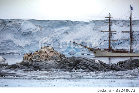 A large ship stands behind stones with penguin.And 32248672