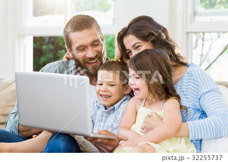 Parents and kids using laptop in living room Parents and kids using laptop in living room 32255737
