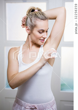 Young woman applying powder on her underarms Young woman applying powder on her underarms 32256359