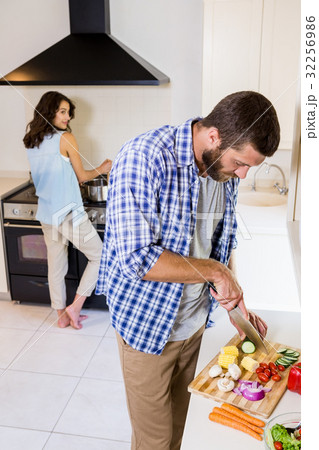 Man chopping vegetables and woman cooking on stove Man chopping vegetables and woman cooking on stove 32256986