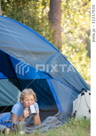 Mature woman laying and drinking on a mug Mature woman laying and drinking on a mug 32257630