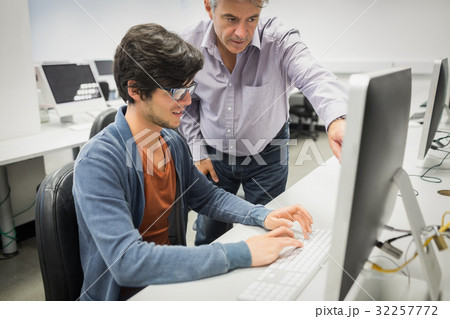 Computer teacher assisting a student 32257772