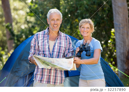 Mature couple smiling and holding binoculars and map Mature couple smiling and holding binoculars and map 32257890