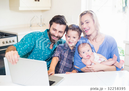 Parents and kids using laptop in living room 32258395