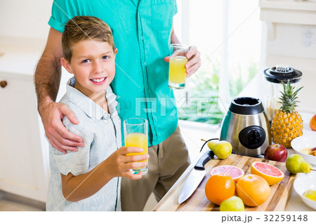 Father and son holding glass of a juice Father and son holding glass of a juice 32259148