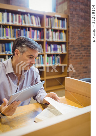 Professor holding digital tablet and reading book Professor holding digital tablet and reading book 32259154