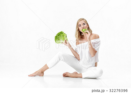 Beautiful blond woman in white blouse eating fresh 32276396