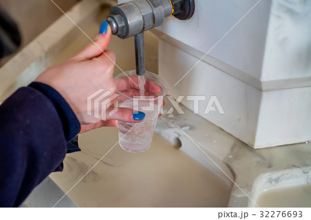 Woman pours mineral water in glass in pump-room Woman pours mineral water in glass in pump-room 32276693