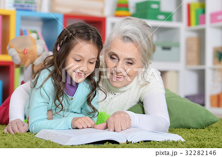 Grandmother reading book with her granddaughter 32282146
