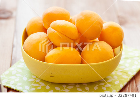 Heap of apricots in wooden bowl on table Heap of apricots in wooden bowl on table 32287491
