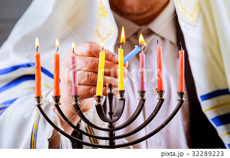 man hand lighting candles in menorah table  32289223