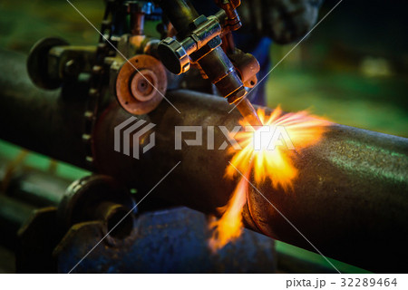 Worker cutting steel pipe with acetylene welding 32289464