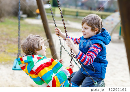 Two little kid boys having fun with chain swing on Two little kid boys having fun with chain swing on 32292161