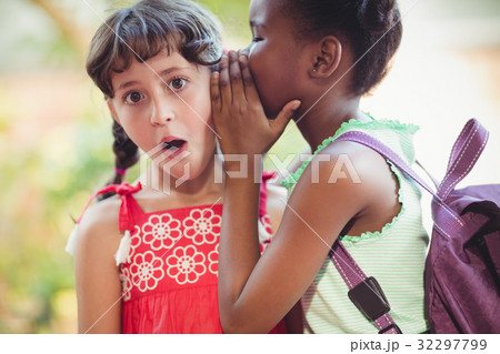 Girl telling a secret to her friend 32297799