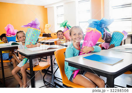 happy pupils sitting at their desk with gifts boxes 32298506